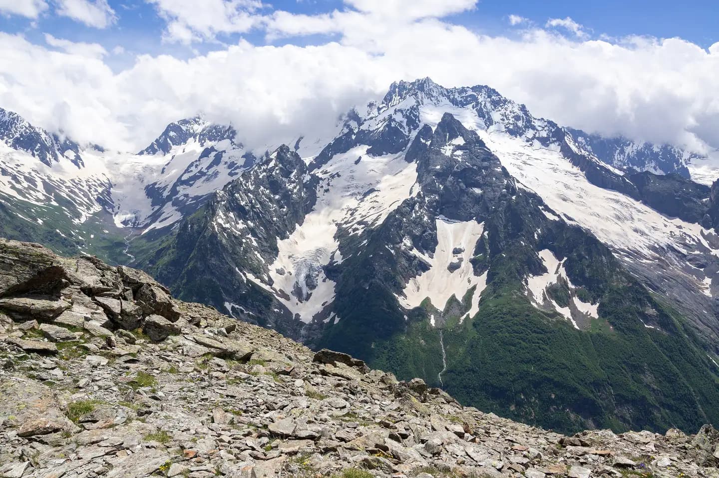 Snow-covered peaks and a glacier in the Caucasus mountains, rising toward a high ridge